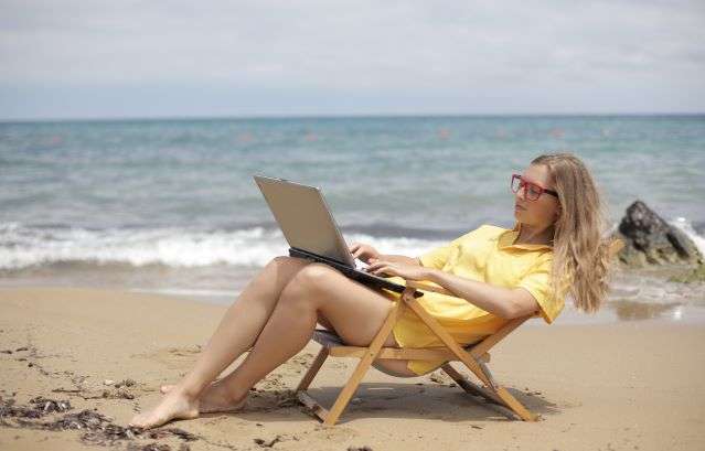 avoid-the-summer-content-slump-white-woman-lounges-on-chair-amidst-beach-sand-and-waves
