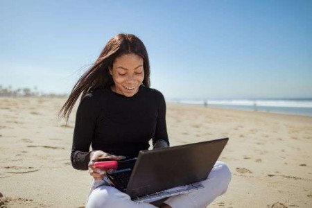 beat-the-summer-content-slump-woman-on-beach-with-laptop-linkeo-web-agency