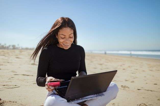 beat-the-summer-content-slump-woman-on-beach-with-laptop-linkeo-web-agency